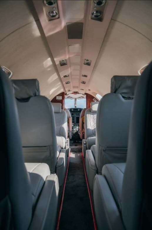 View down the aisle of the aircraft cabin, showing leather seats.