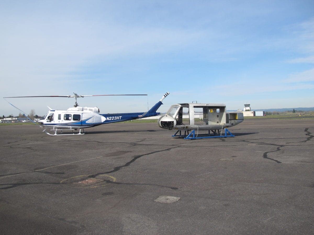 Helicopter N223HT and a fuselage on the tarmac.