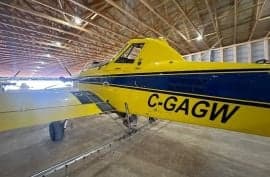 Cropduster aircraft in a hangar with yellow and blue paint scheme.