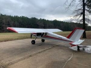 A white and red aircraft is parked on a concrete surface.