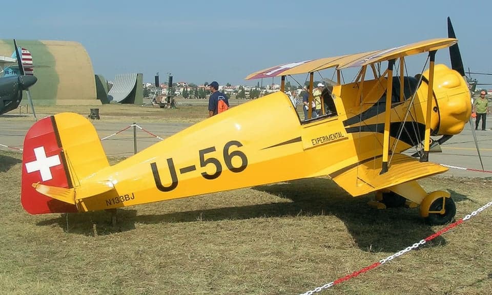 A yellow biplane with Swiss markings on display.