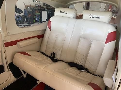 The rear seats of the aircraft are white leather with red accents and headrests labeled 'Cardinal'.