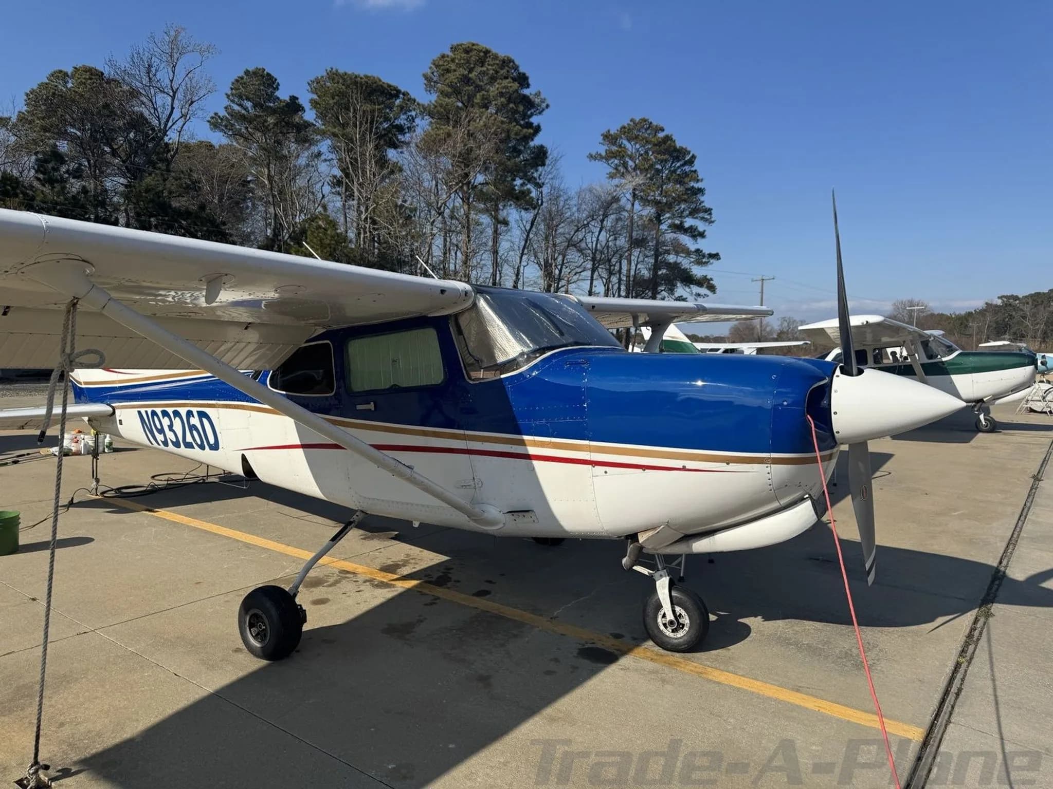 A front-right view of the blue and white Cessna 182 Skylane N9326D parked on an airfield.