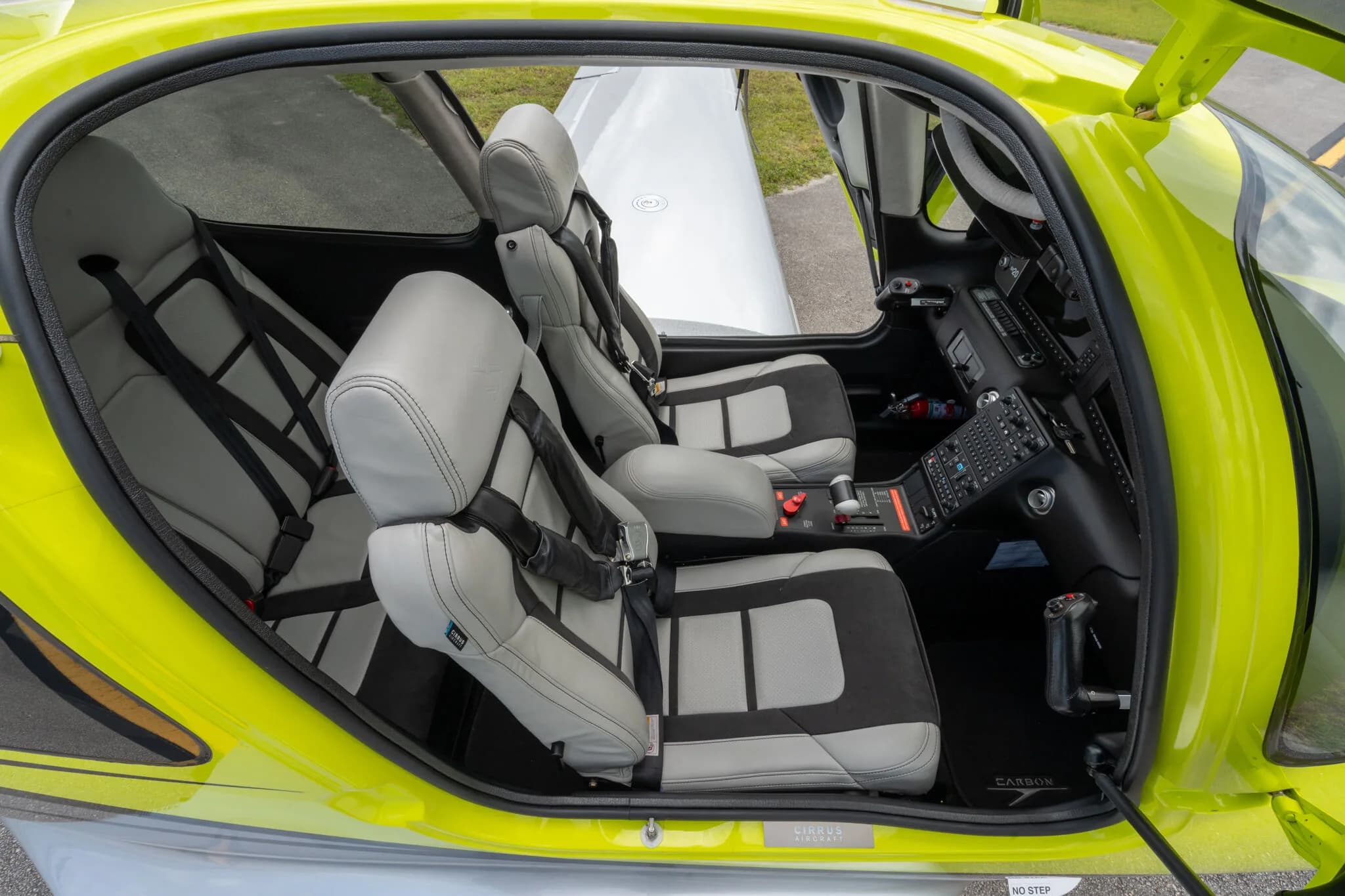 Interior view of the Cirrus SR20 cabin, showing grey and black seats with seatbelts and a partial view of the cockpit.