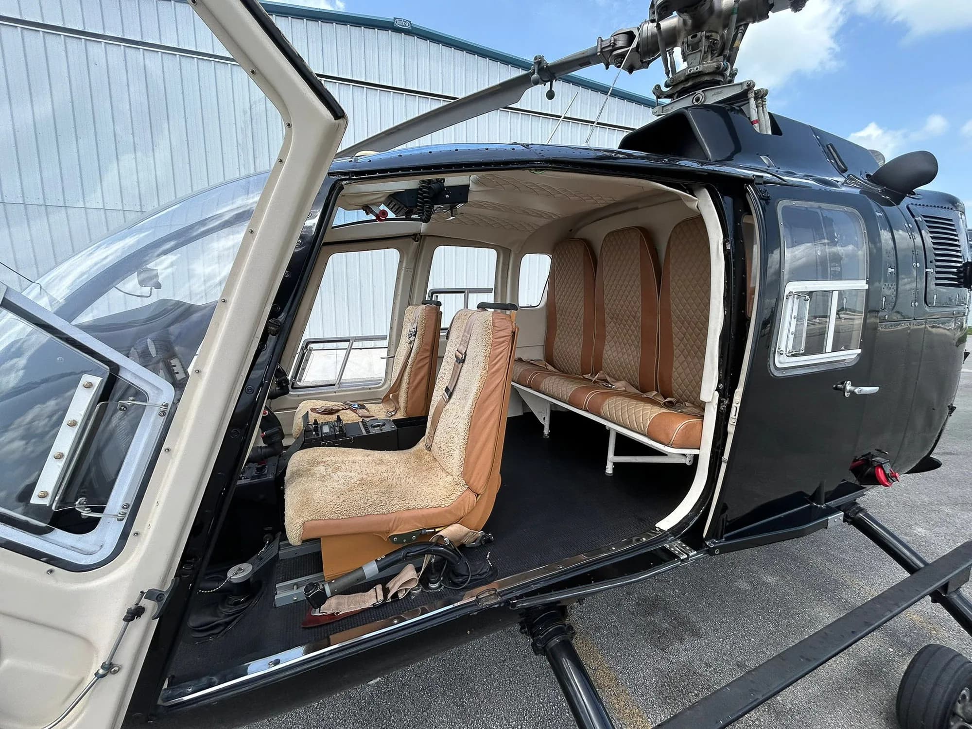 View of the helicopter's cabin interior with tan seats and an open door.