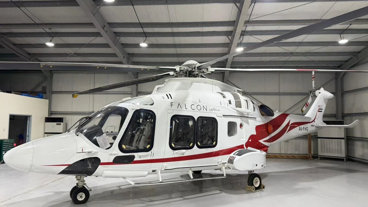 Side angle view of the A6-FHG helicopter parked inside a hangar.