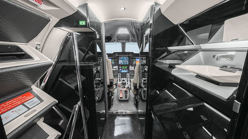 View from the aircraft cabin looking into the modern cockpit with multiple display screens.