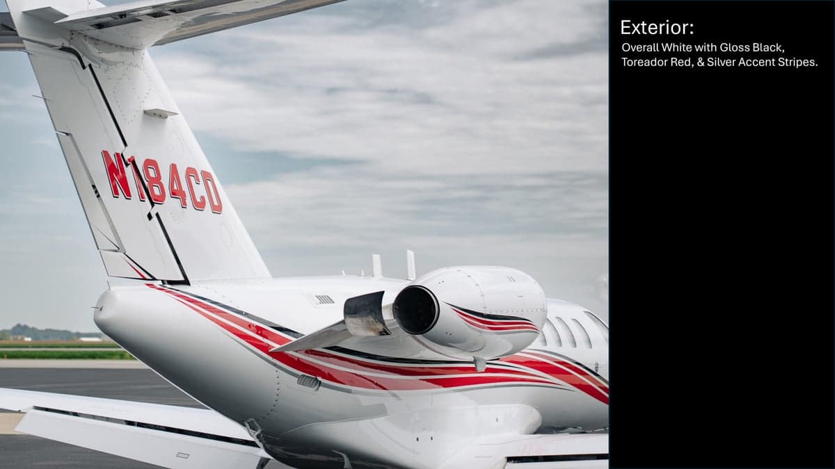 Close up of the tail of a white Citation CJ2 aircraft with red stripes, showing the registration number.