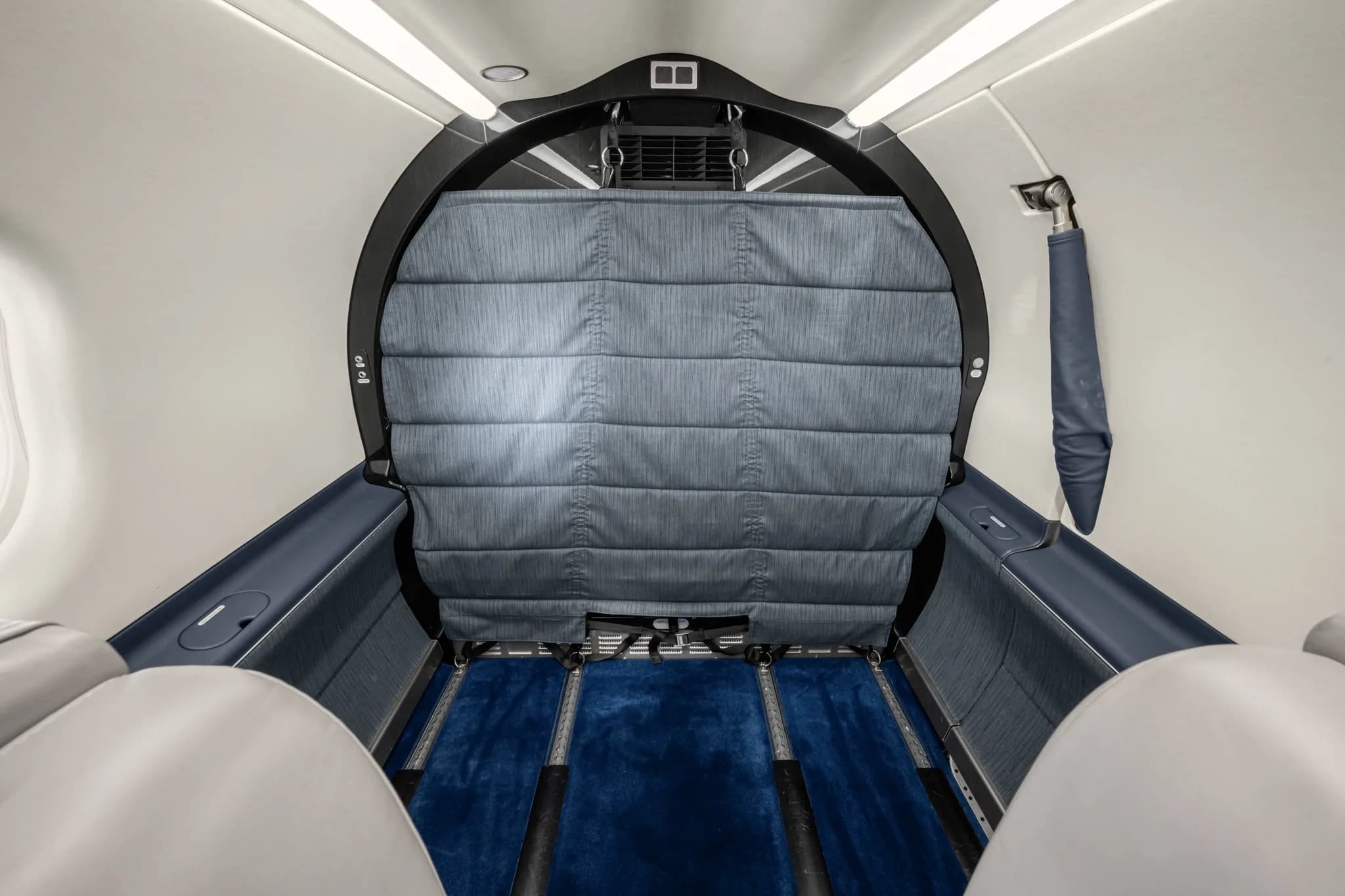 The aircraft's rear cabin area is configured for cargo, with a padded partition and blue floor tracks.