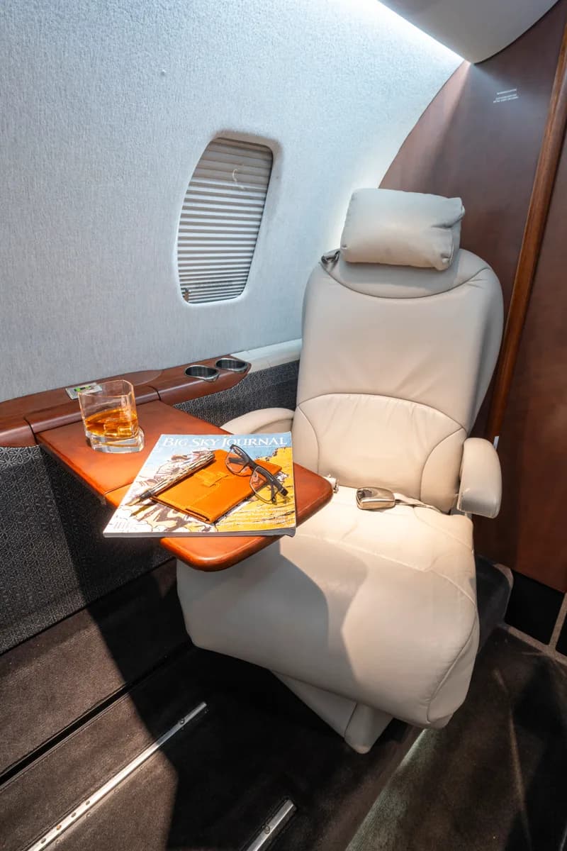 A view of the aircraft's interior, featuring a leather seat and a wooden cabinet with a sink.