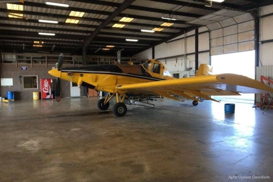 A yellow Air Tractor crop duster sits in a hangar.