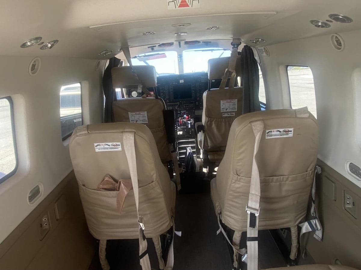 The interior of the aircraft features forward-facing seats and a view of the cockpit.