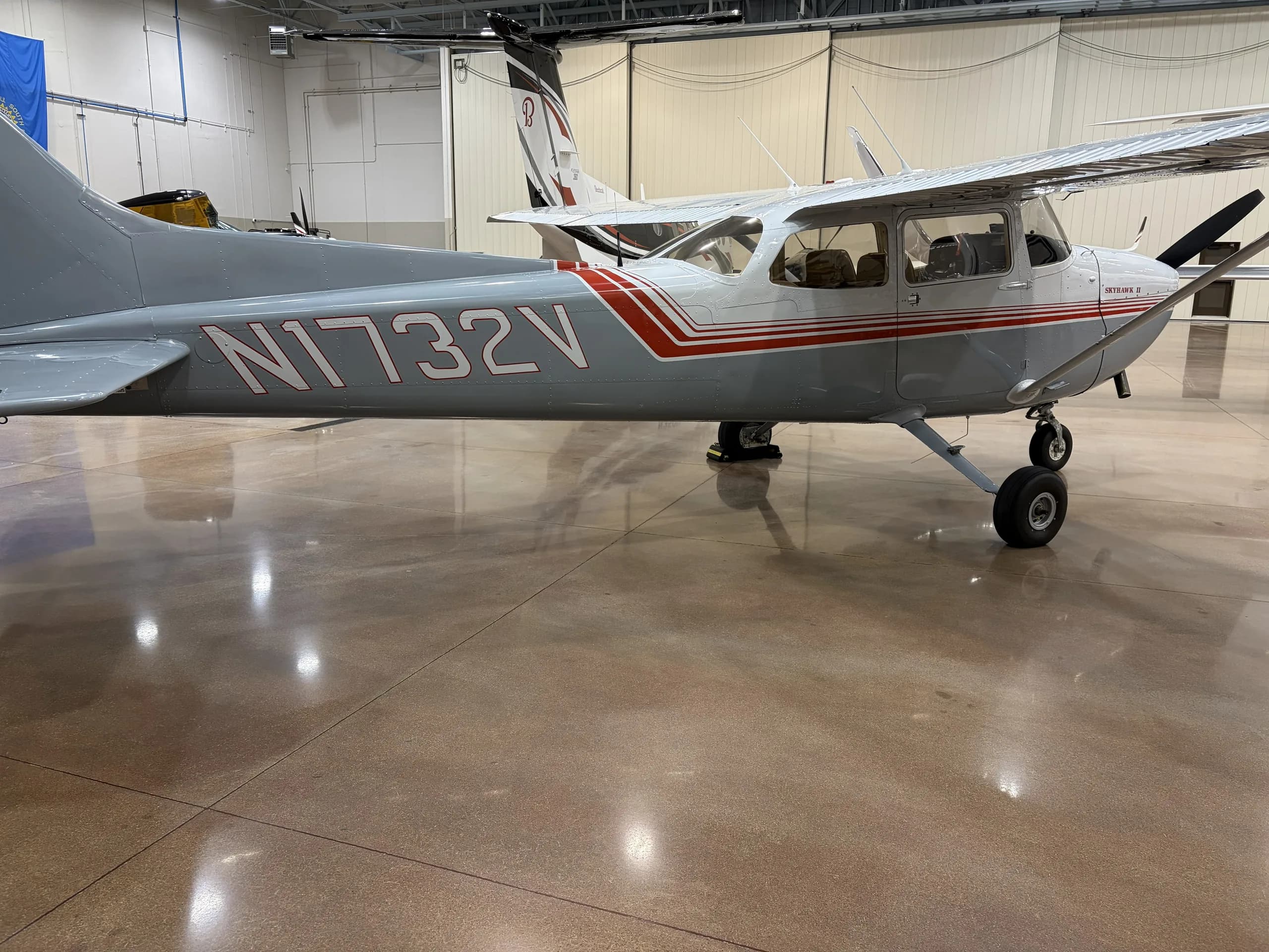 Cessna 172 with gray and red paint scheme in a hangar.