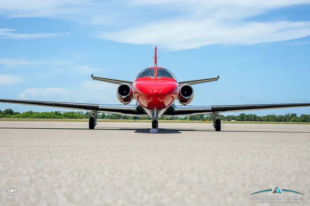 A low-angle front view of the red and black Cessna Citation V (N300CH) jet on a tarmac.