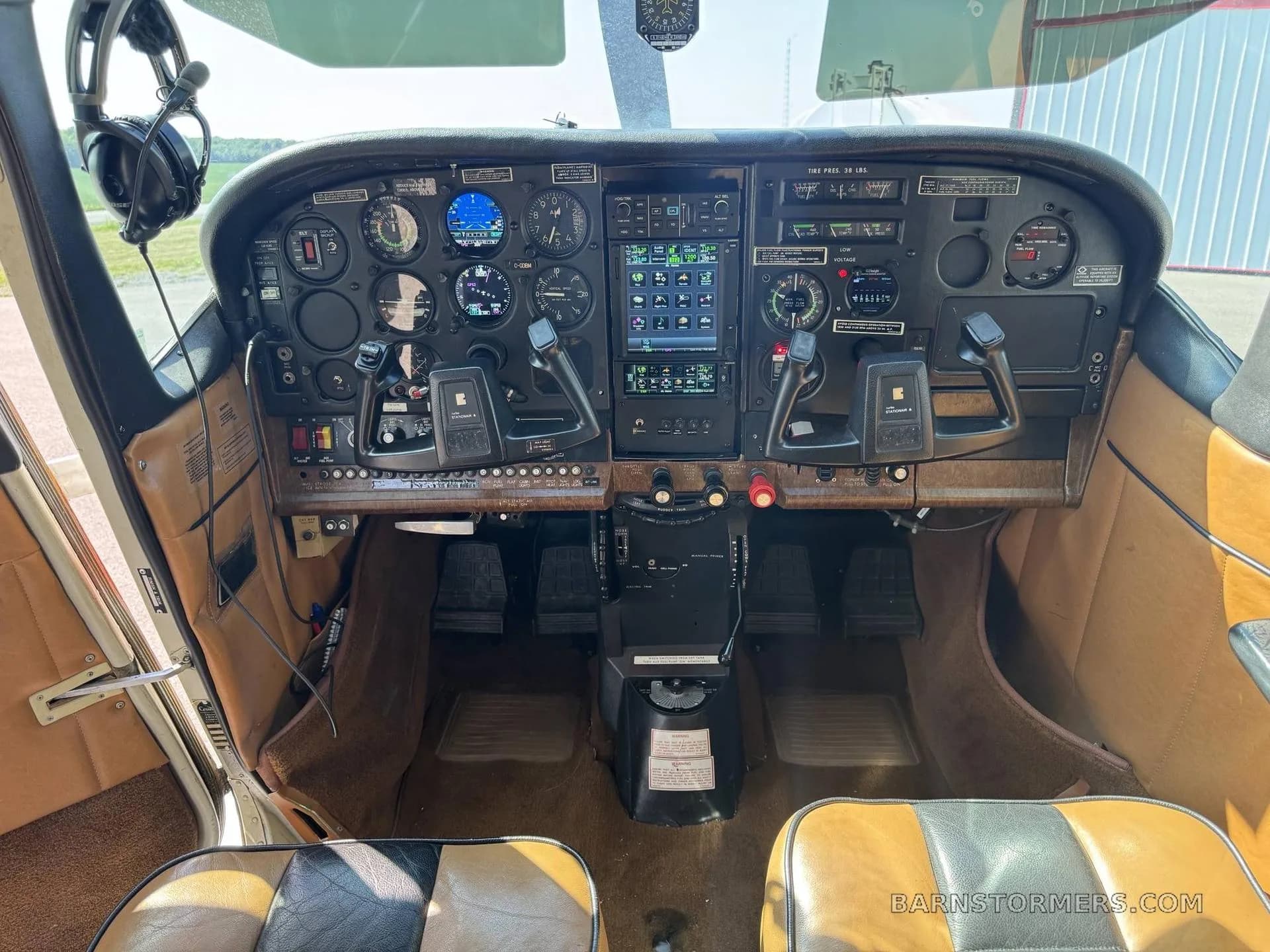 A full view of the Cessna Stationair 6 cockpit, showing the instrument panel, yokes, and tan seats.