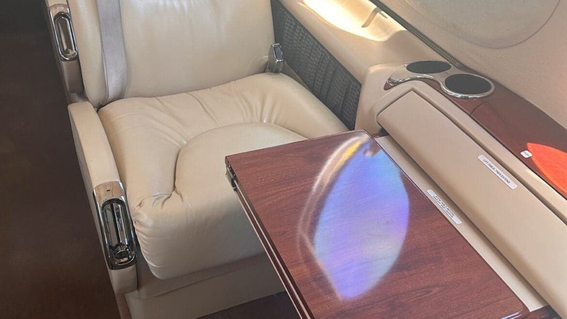 A close-up of a leather seat and wooden table in the King Air 350 cabin.