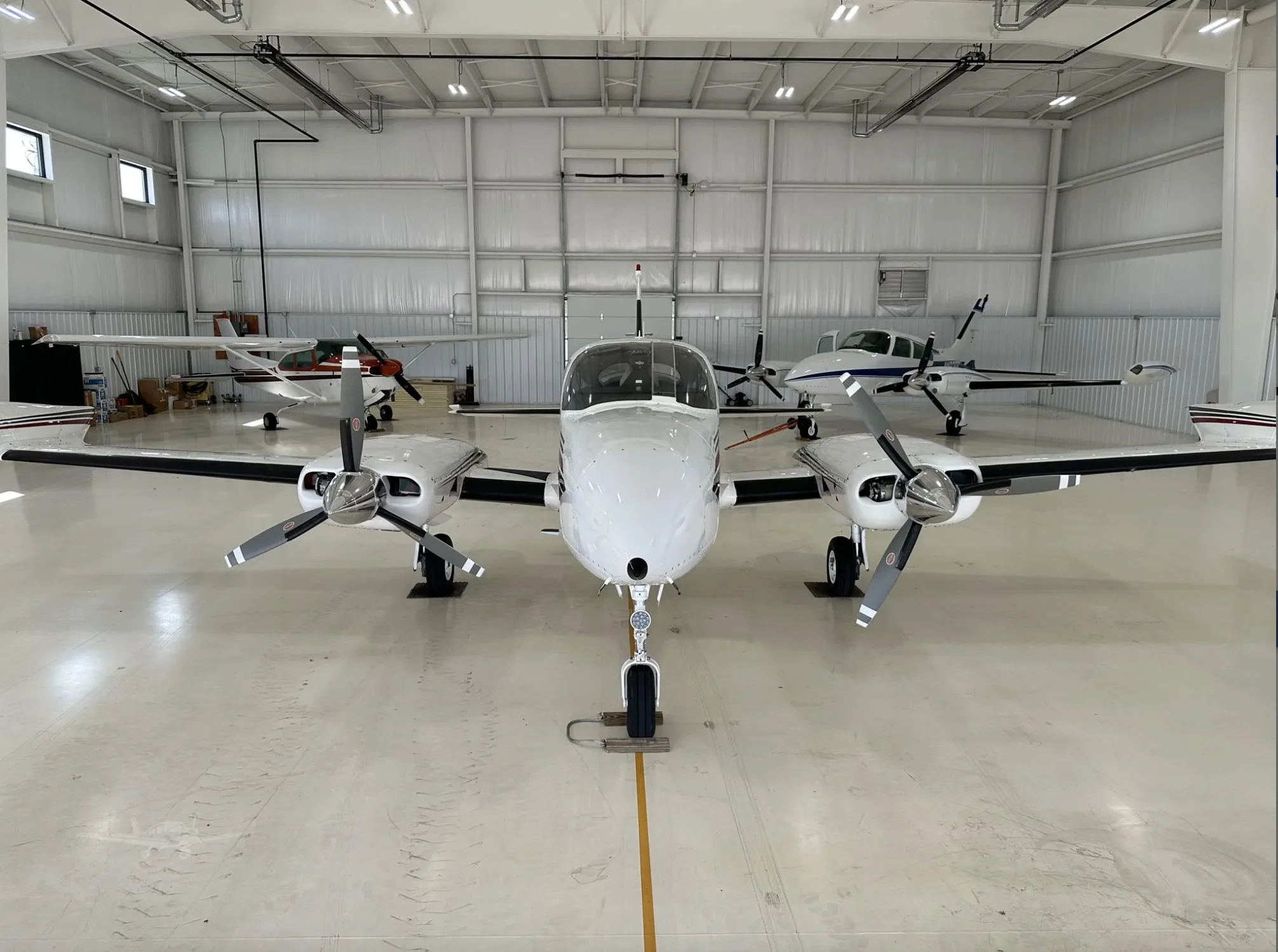 A head-on view of the white and maroon twin-engine aircraft, N916MD, inside a hangar.
