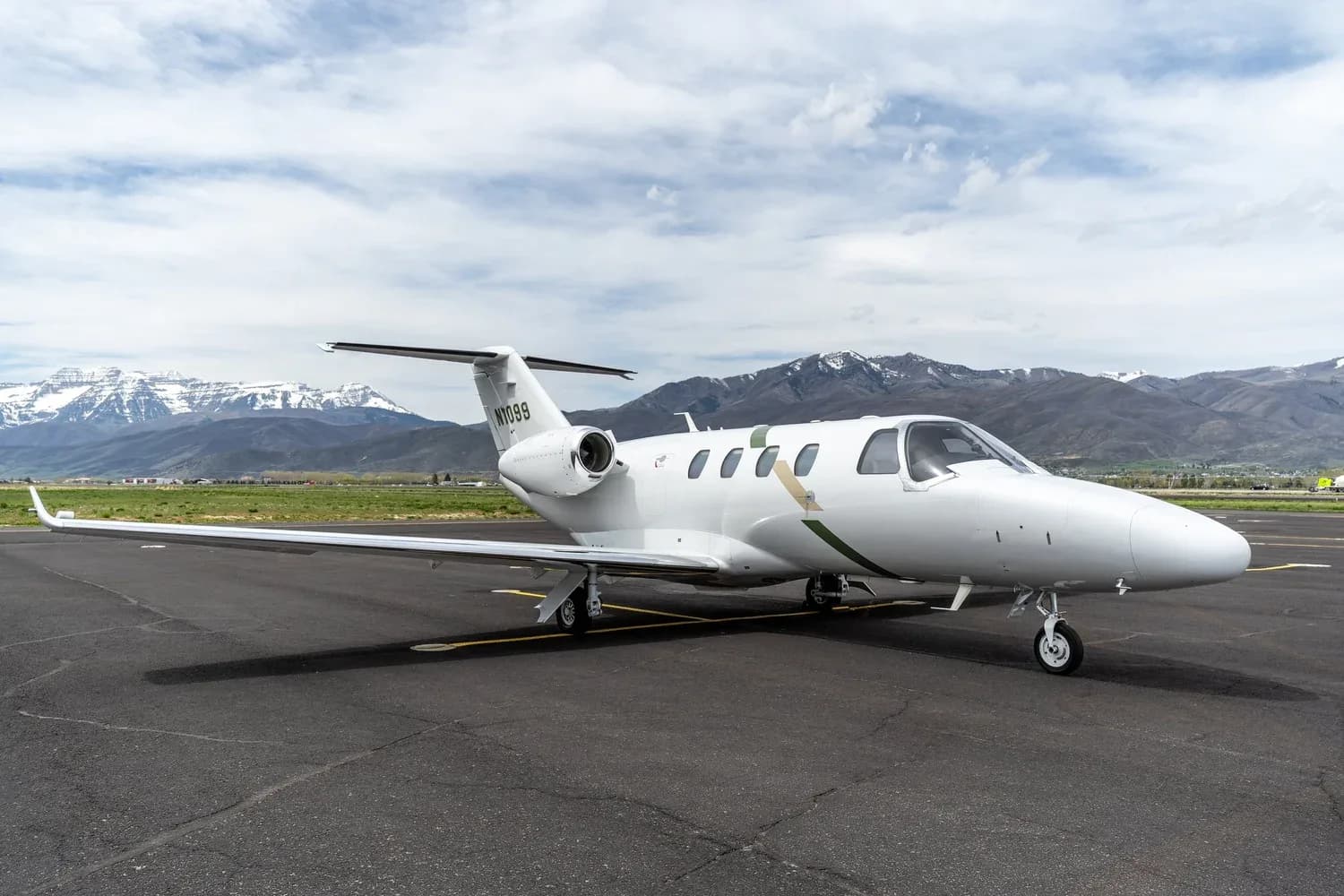 Cessna Citation CJ3+ aircraft N1099 on the tarmac with mountains in the background.