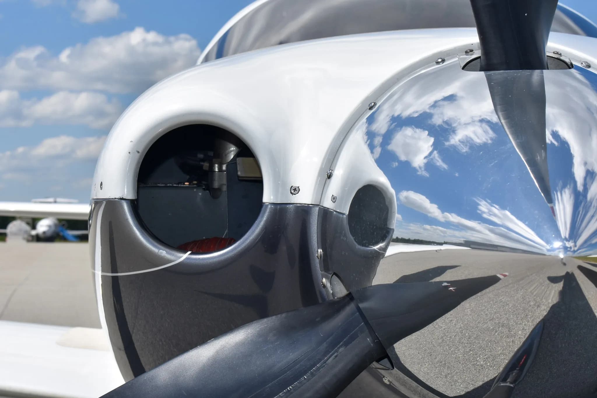 A very close-up view of the propeller spinner and air intake on the nose of a white and dark grey Cessna TTx (Corvalis 400) aircraft.