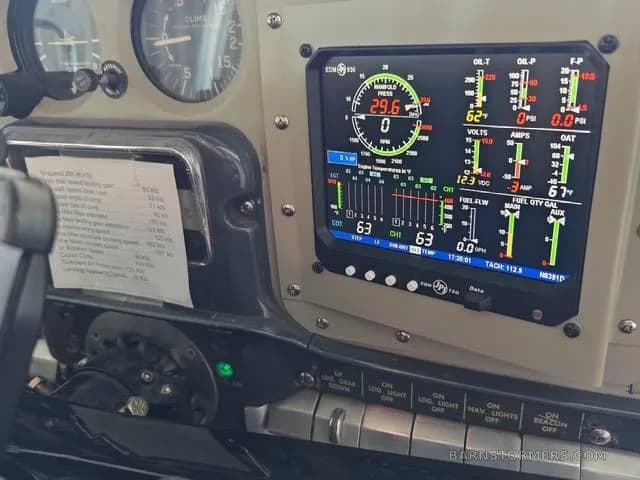 A close-up of an aircraft cockpit showing a modern digital engine monitor display and analog gauges.