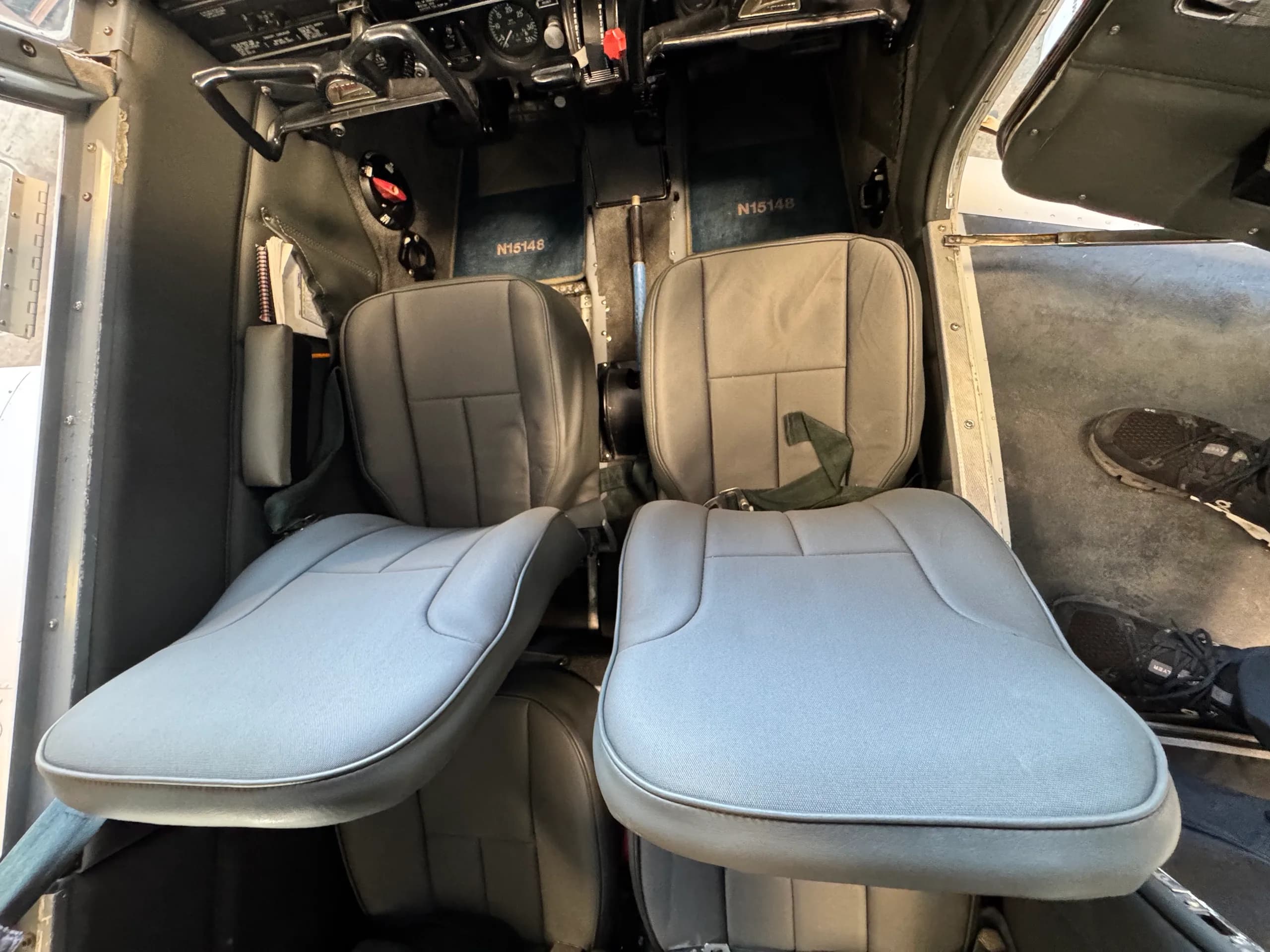 View of the grey pilot and co-pilot seats inside the cockpit of the N15148 aircraft.