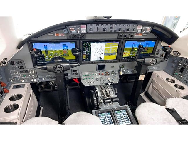 The cockpit of an aircraft features multiple display screens and controls.