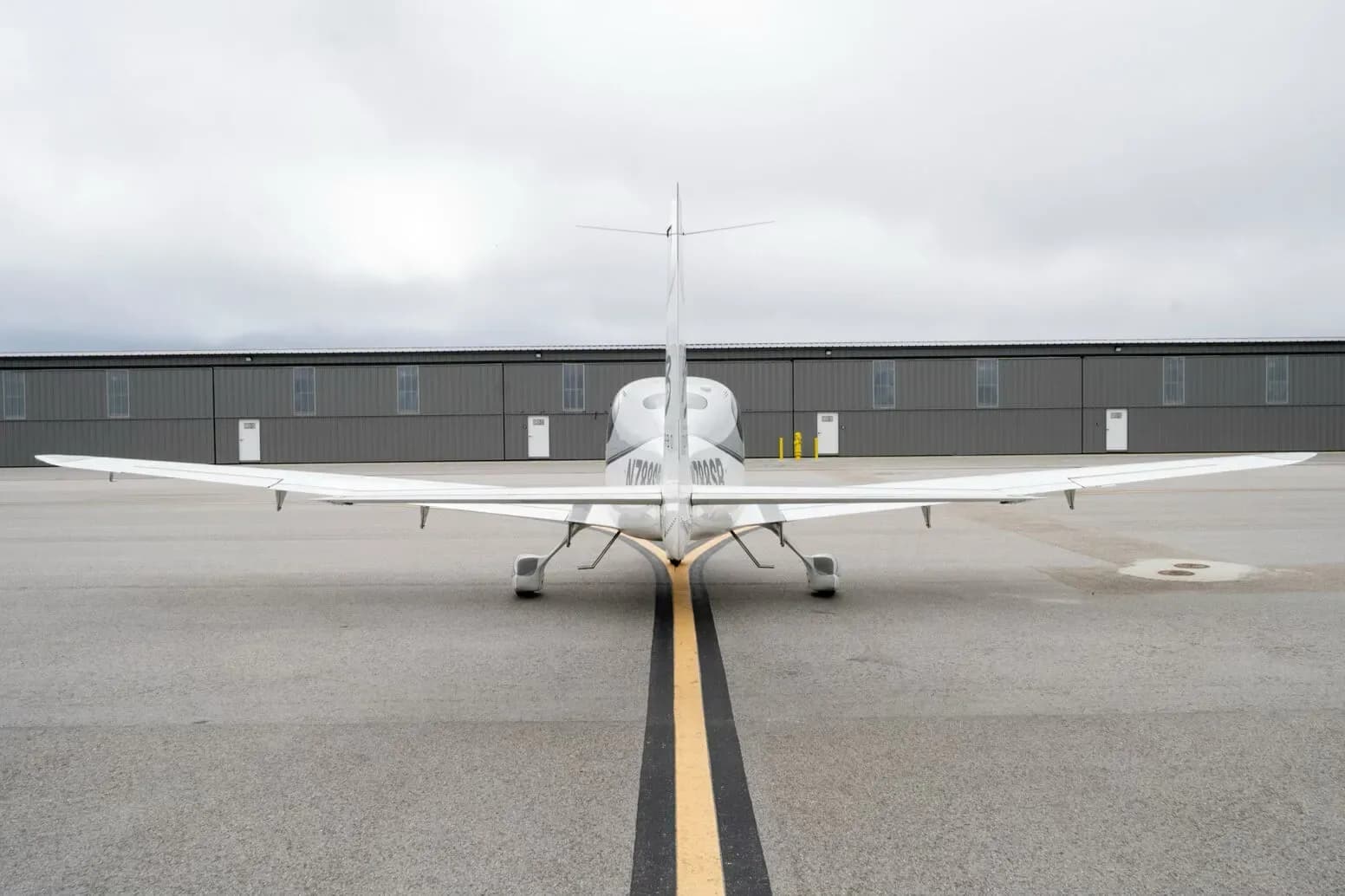 Rear view of a white and grey Cirrus SR22 G3 Turbo aircraft, N788SR, parked on an airfield.