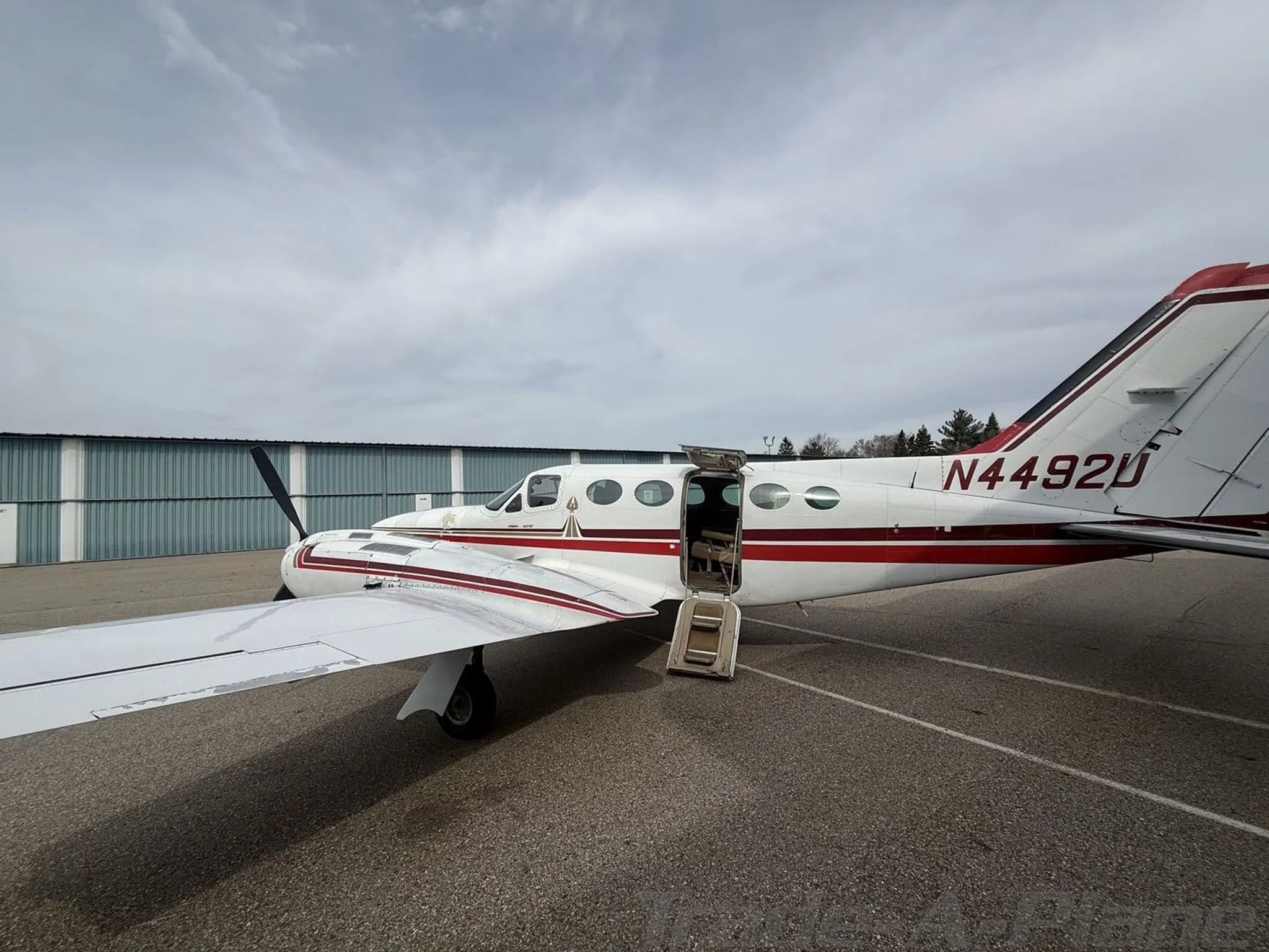A white and red twin-engine Cessna 414 Chancellor aircraft, registration N4492U, parked on an asphalt ramp with its passenger door open.