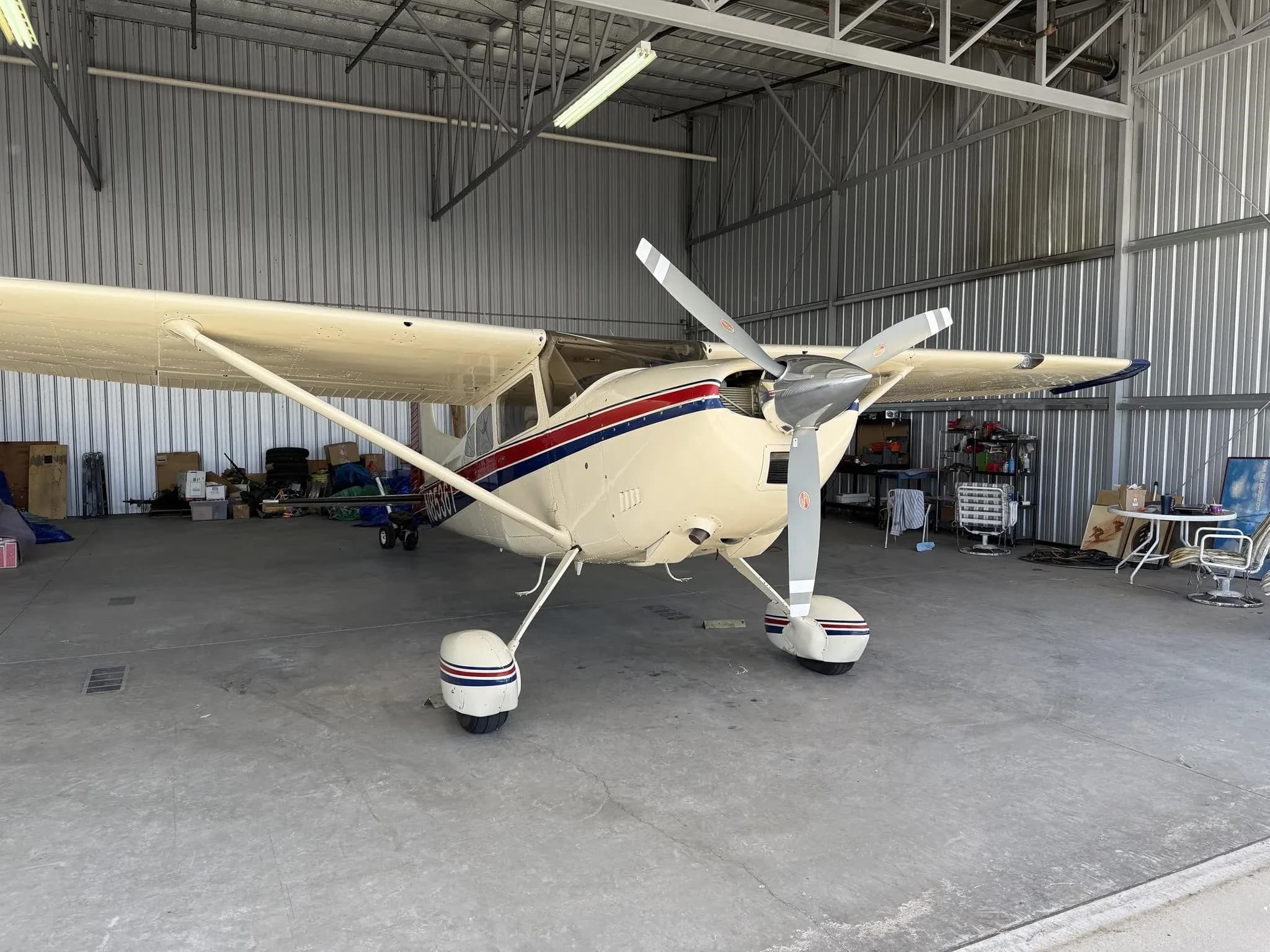 Front view of a white Cessna aircraft with red and blue stripes, registration N8536T, inside a hangar.