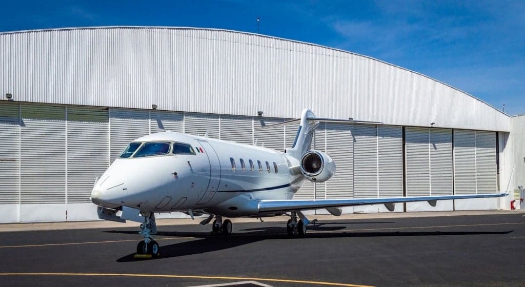 A Bombardier Challenger 300 parked on the tarmac in front of a hangar.