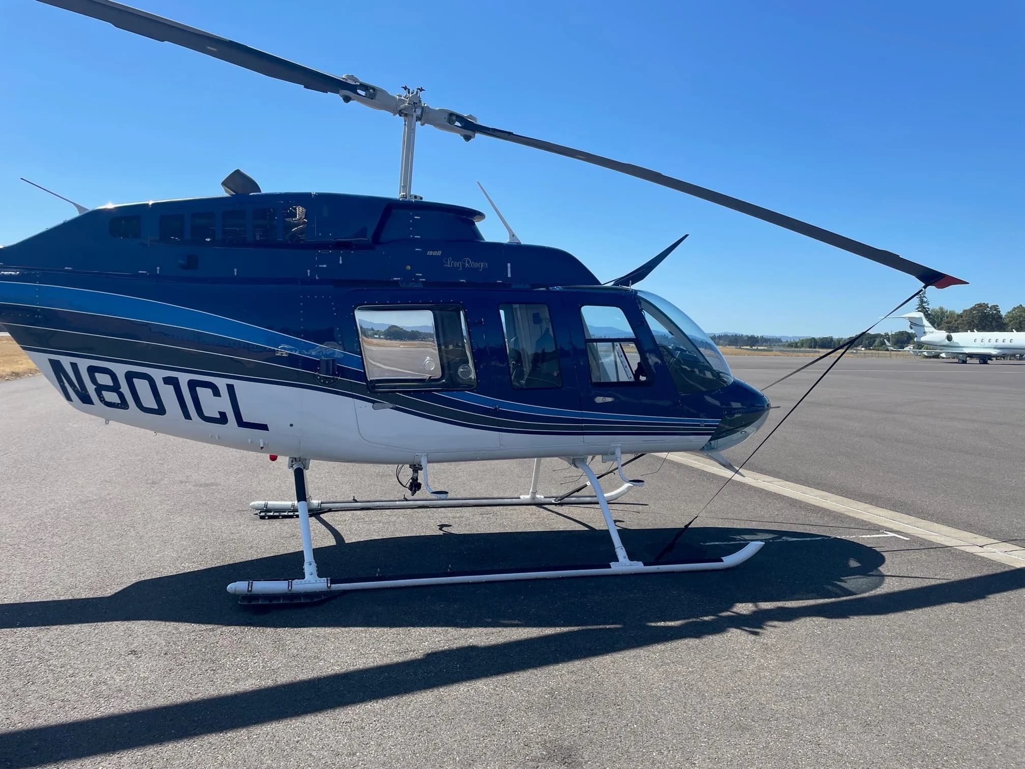 Close-up of a Bell 206B Jet Ranger with blue and white paint scheme, parked on the tarmac.