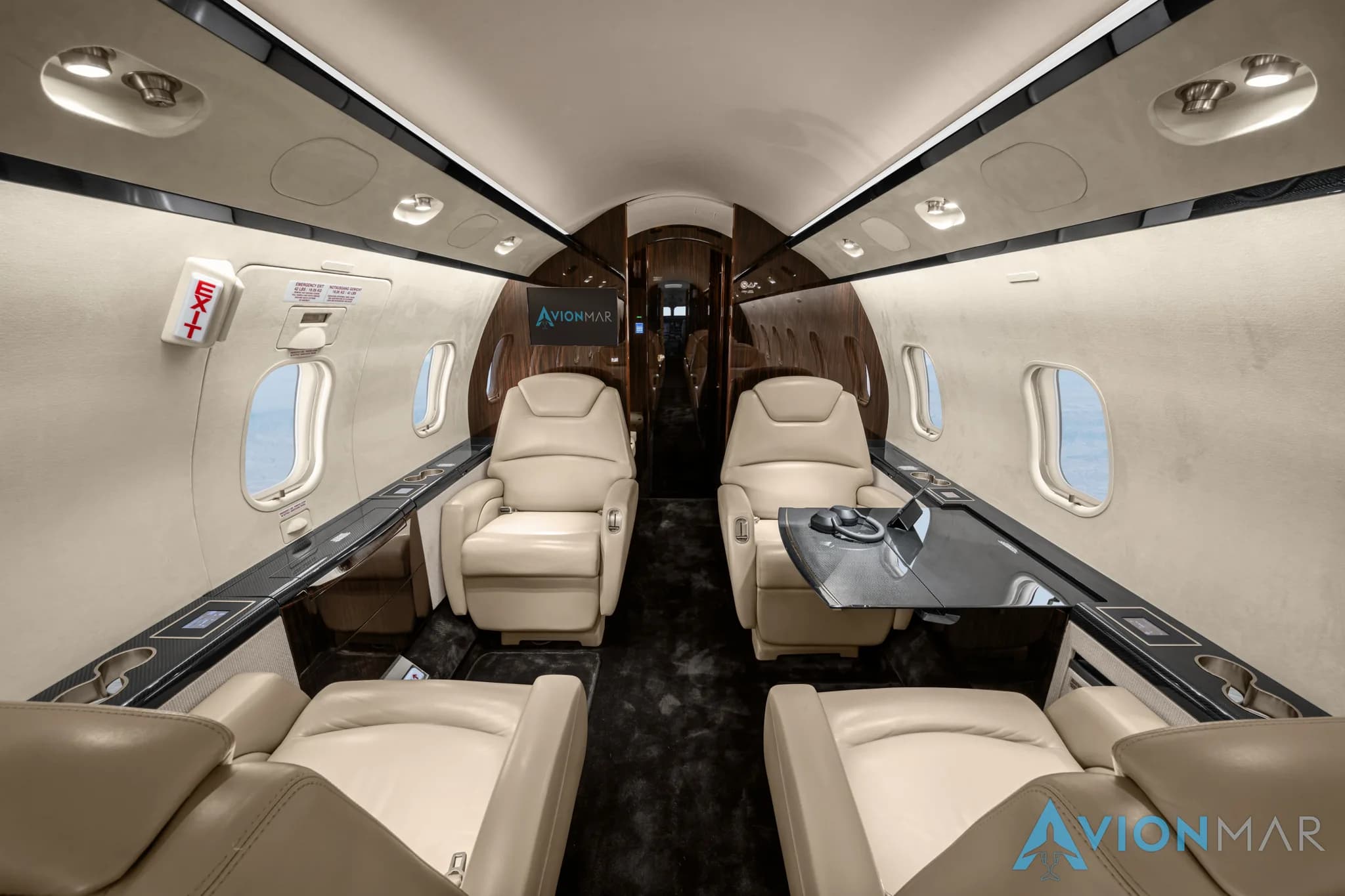 The luxurious interior of a private jet cabin with cream leather seats and a table, viewed from the rear.
