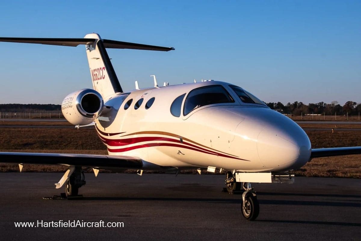 A Cessna Citation Mustang with a white and red paint scheme is parked on the tarmac.