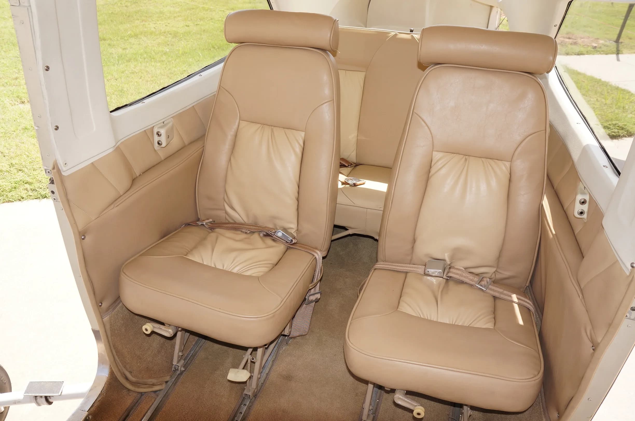 The tan leather front passenger and pilot seats of a small aircraft cabin.