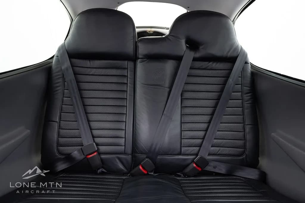 Close-up view of the black leather rear seats with seatbelts in the Cirrus SR20 cabin.