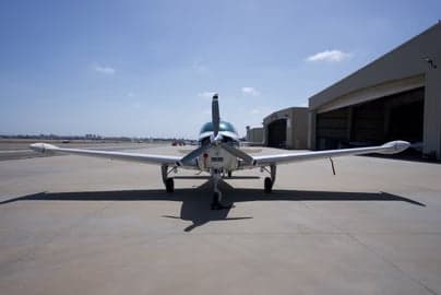A Beechcraft Bonanza aircraft parked on the tarmac on a sunny day.