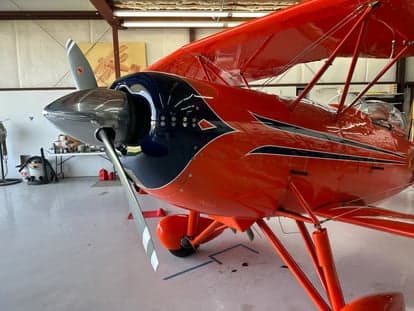 The cockpit of an orange biplane with a full instrument panel.