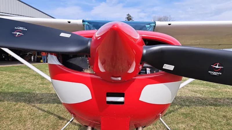 Close up of the propeller and nose of a red and white Cessna.
