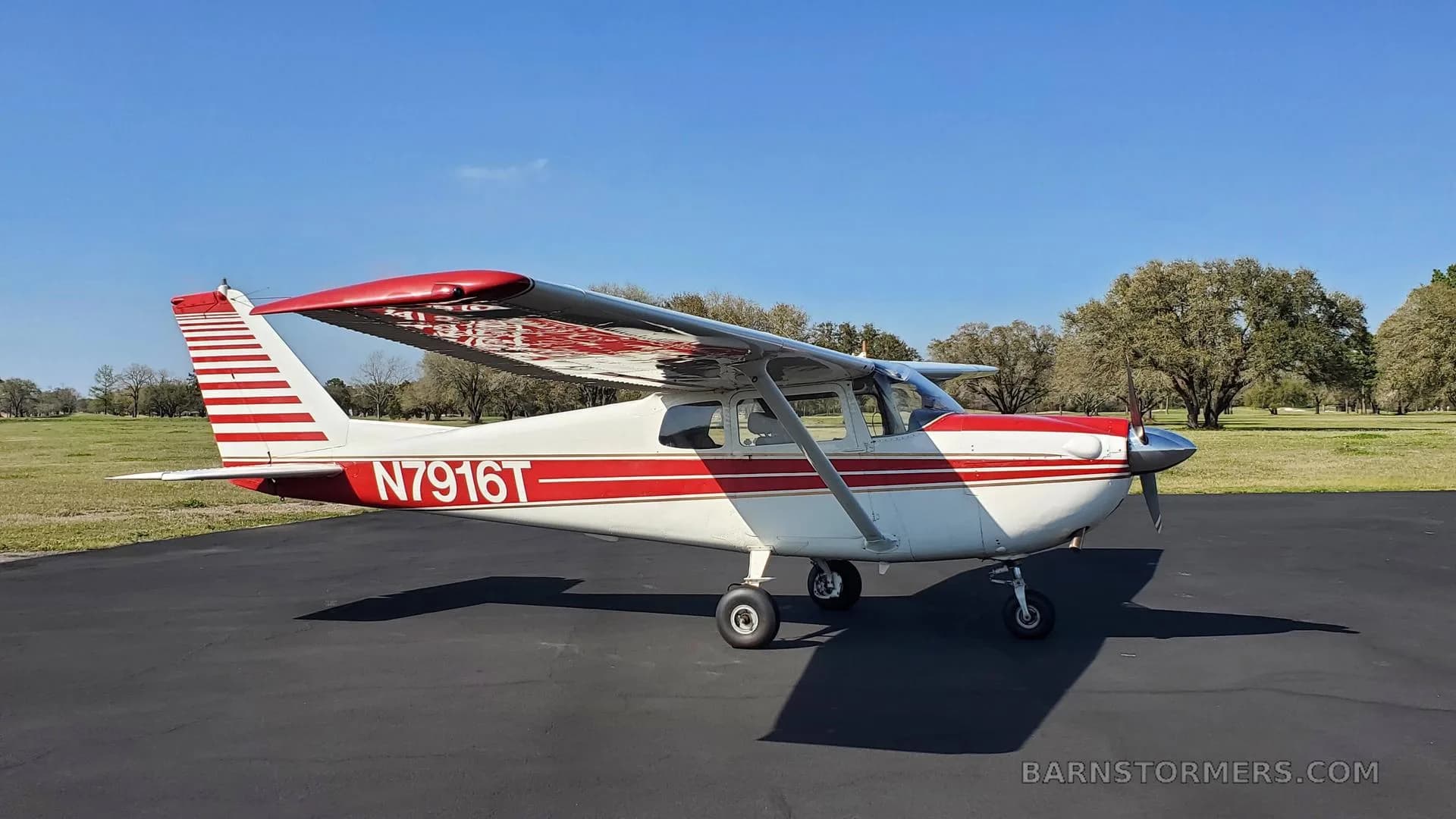 A white and red Cessna 172 with registration N7916T parked on an asphalt pad, viewed from the front-left.