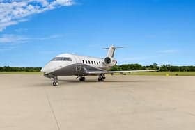 A white private jet parked on a runway.