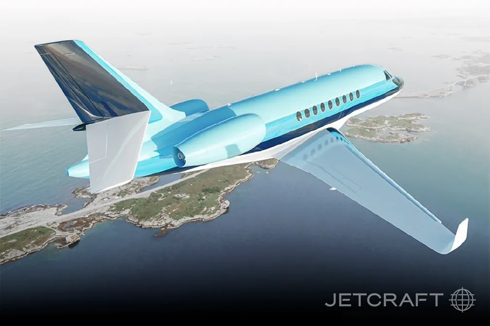 A light blue and white Dassault Falcon 900EX aircraft flying over a coastline, with the "JETCRAFT" logo at the bottom.