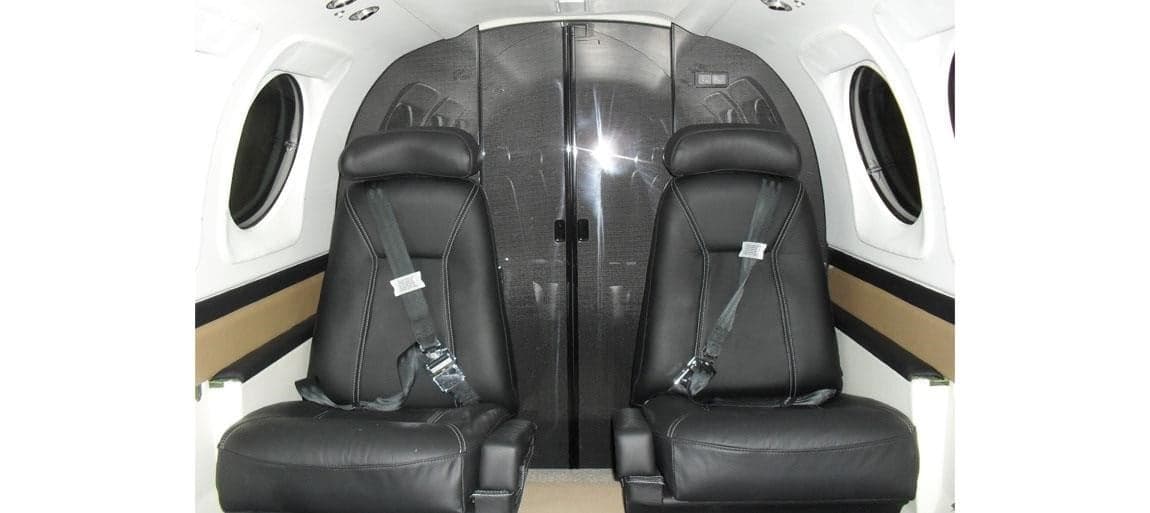 Two black leather seats in the cabin of a Beechcraft King Air.