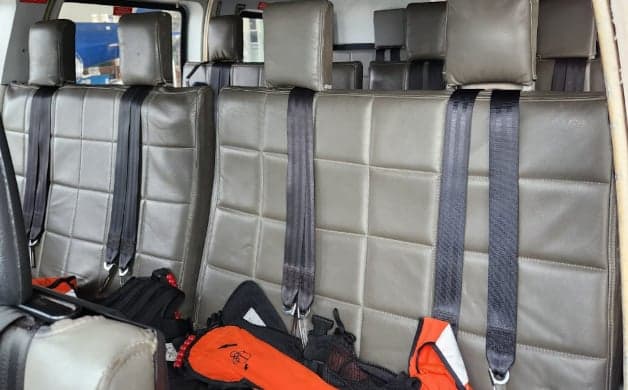 The helicopter's interior features passenger seating with safety equipment.