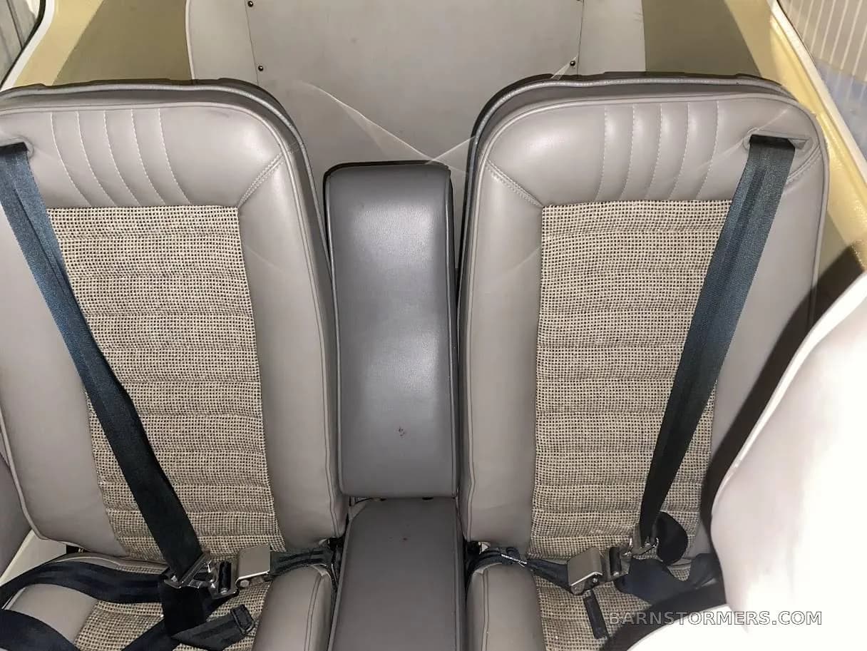 Overhead view of two light gray aircraft cabin seats with fabric inserts and black seatbelts.