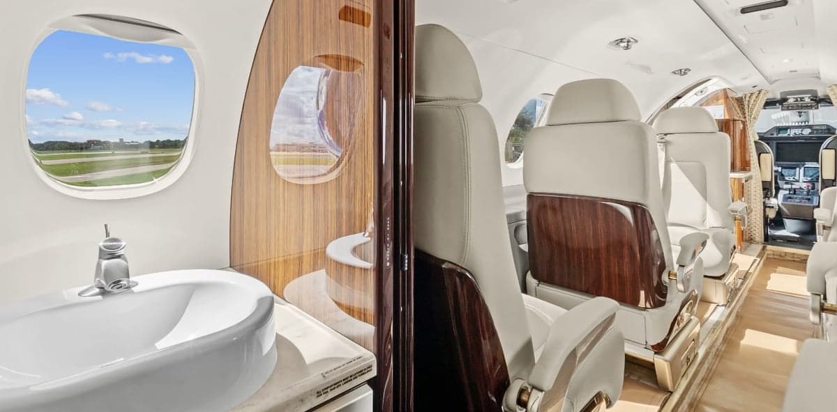 The interior of a Phenom 300 aircraft showing the lavatory and seating.