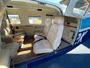 Aircraft interior featuring cream-colored leather seats and an open door.