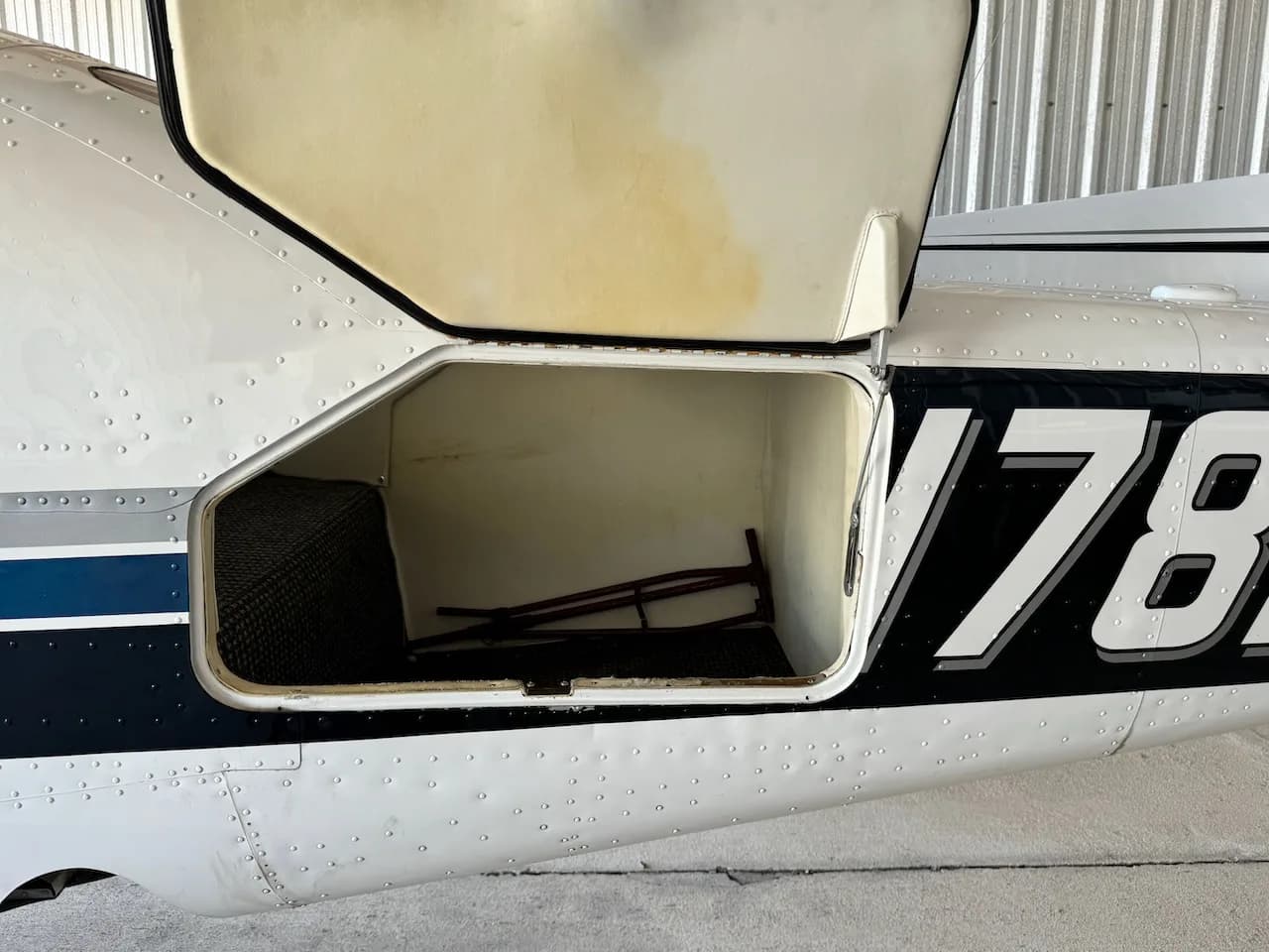 A close-up view of an open baggage compartment on the side of a white aircraft fuselage.