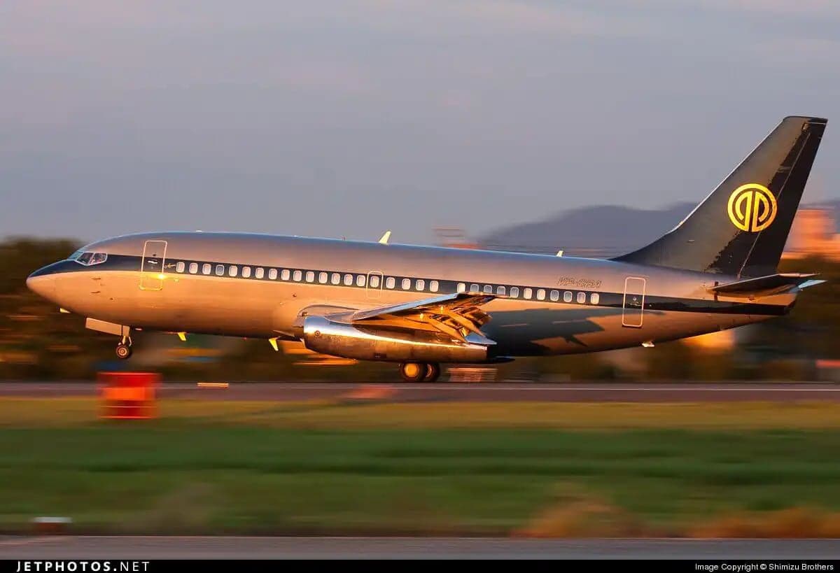 A Boeing 737 in a gray and black livery takes off from a runway.