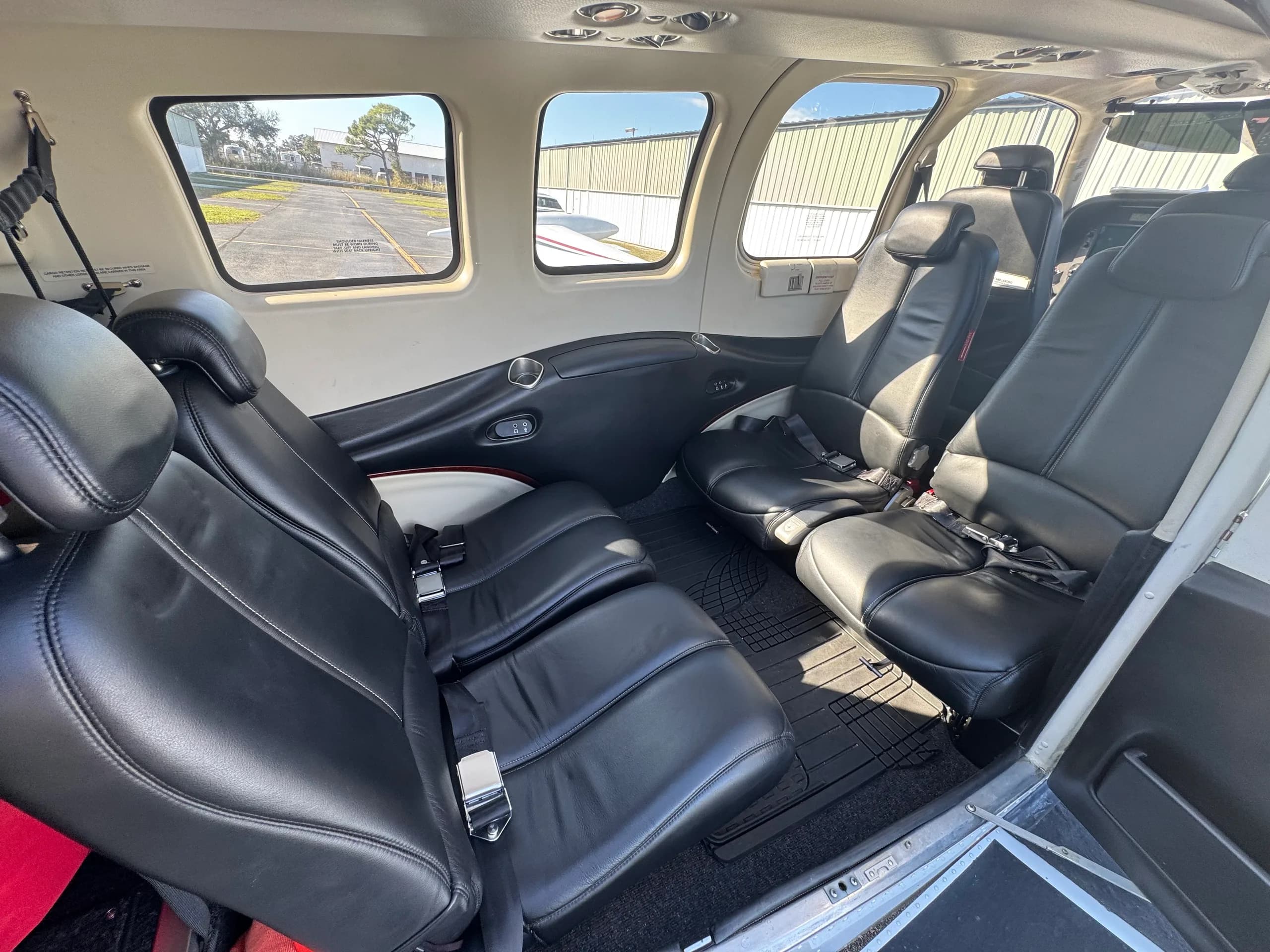 The rear cabin of a Beechcraft Bonanza with four black leather seats and large windows.