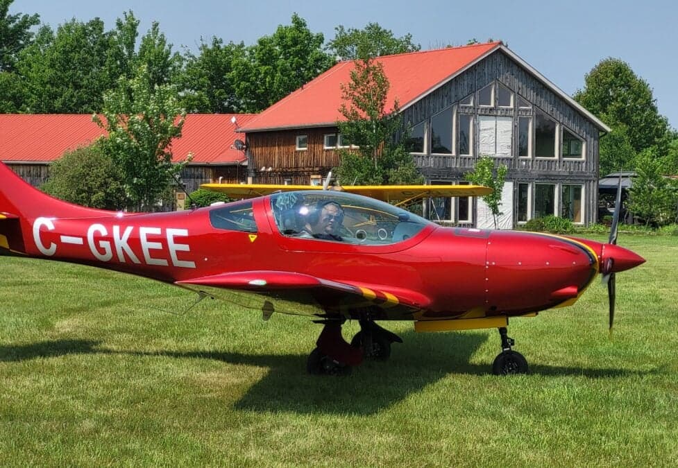 Side view of a red VL3 Evolution aircraft parked on a grassy field.